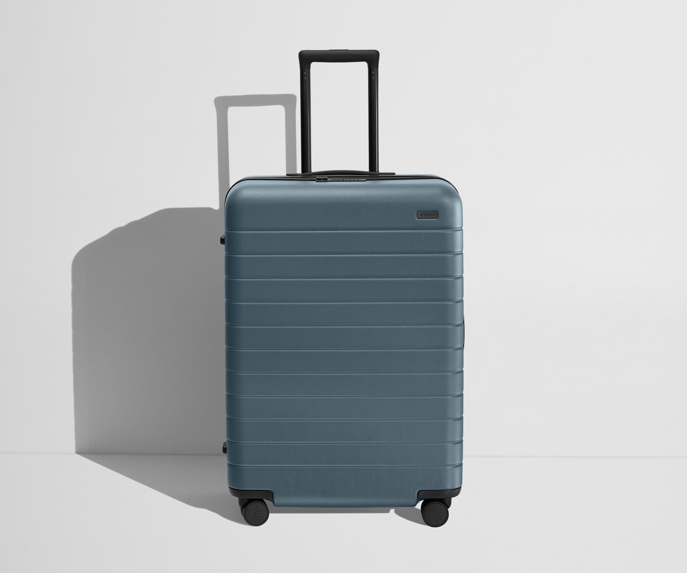 Front product view of The Medium Flex suitcase in Coast Blue with raised handle